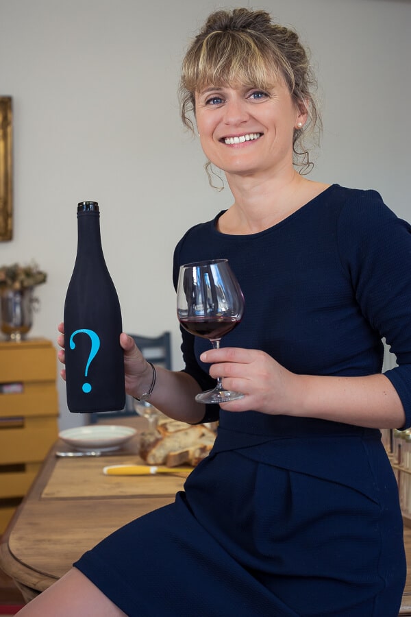 Valéria Naudin tenant un verre de vin rouge et une bouteille de Bourgogne